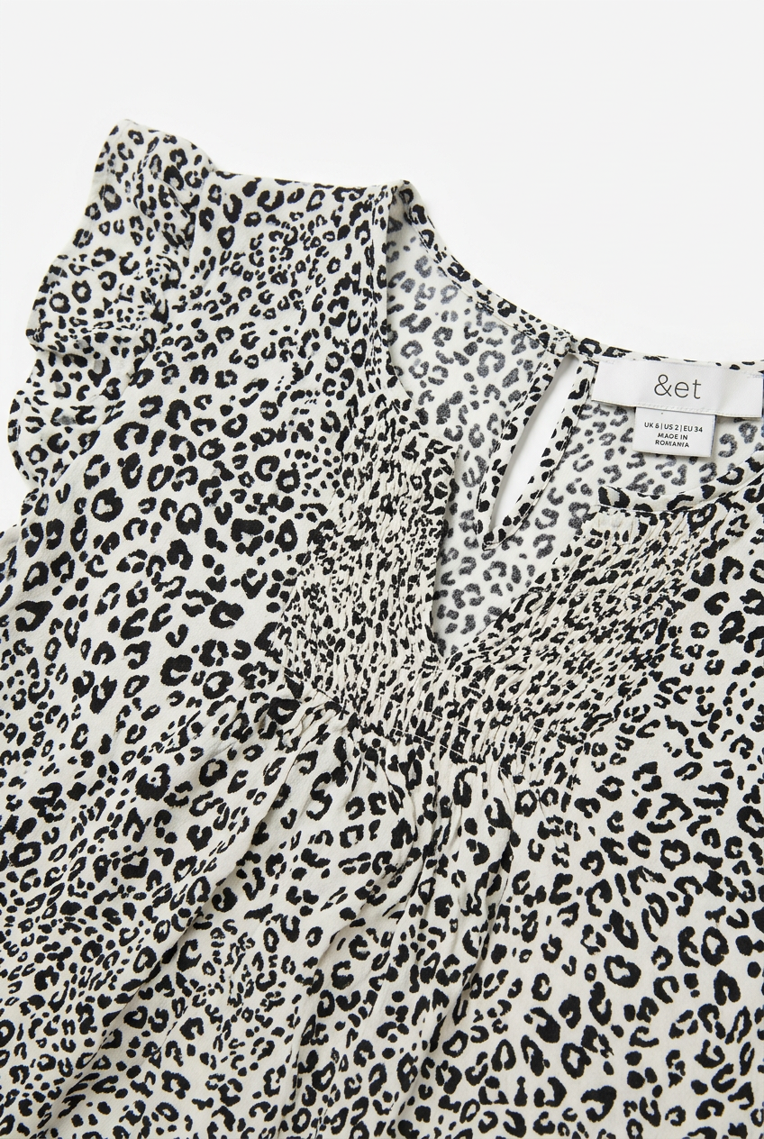 White leopard print blouse – V-neck and smocked chest detail close-up, white background
